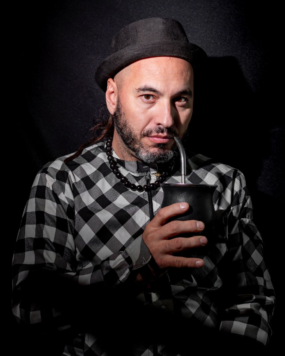 Retrato de Marcos Rodríguez con sombrero y mate, sobre fondo oscuro